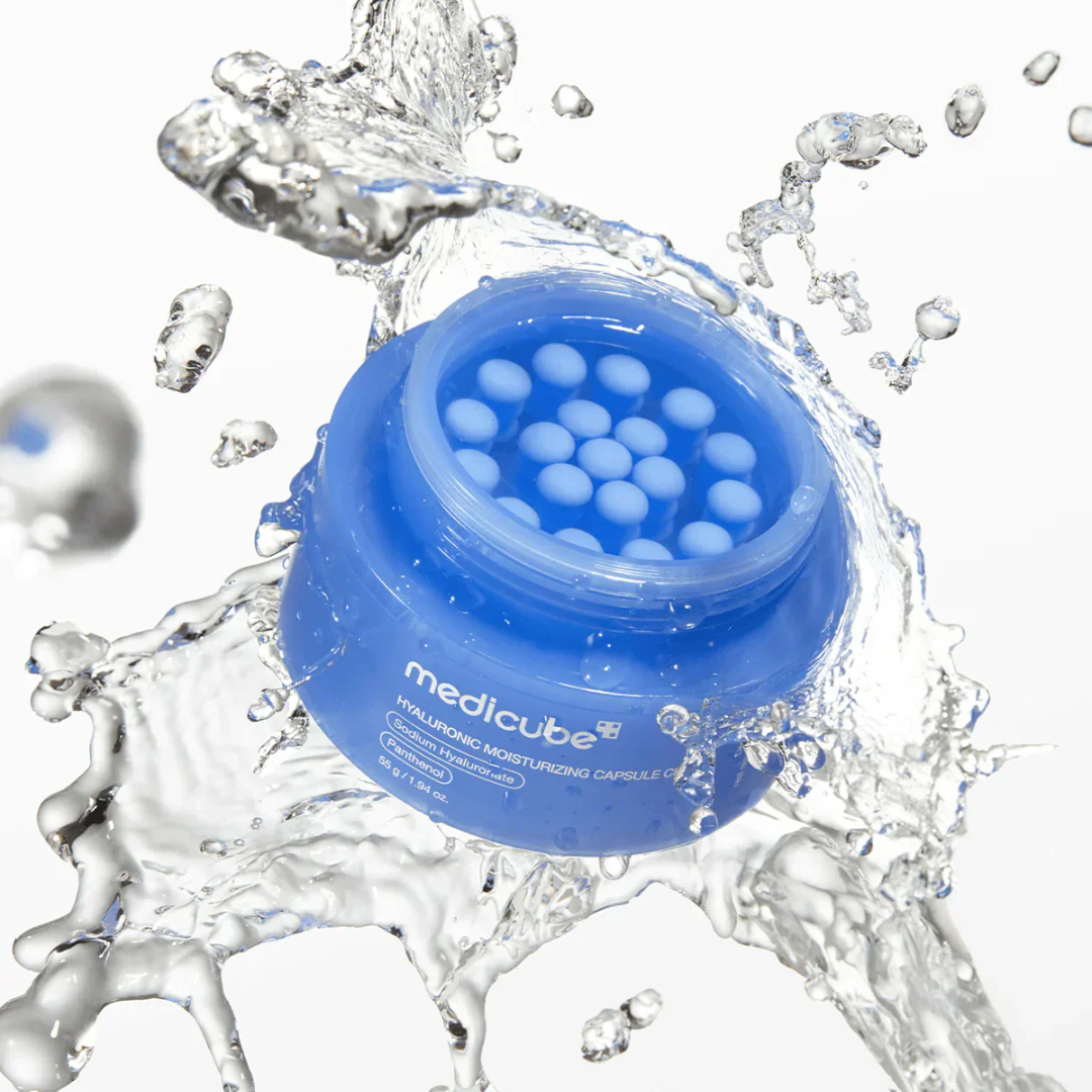 Blue jar of medicube cosmetic product with water splashes on a white background