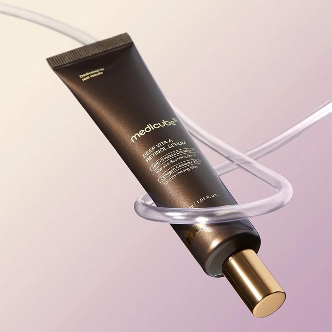 Medicube skincare serum tube on a clear stand with a soft pink background