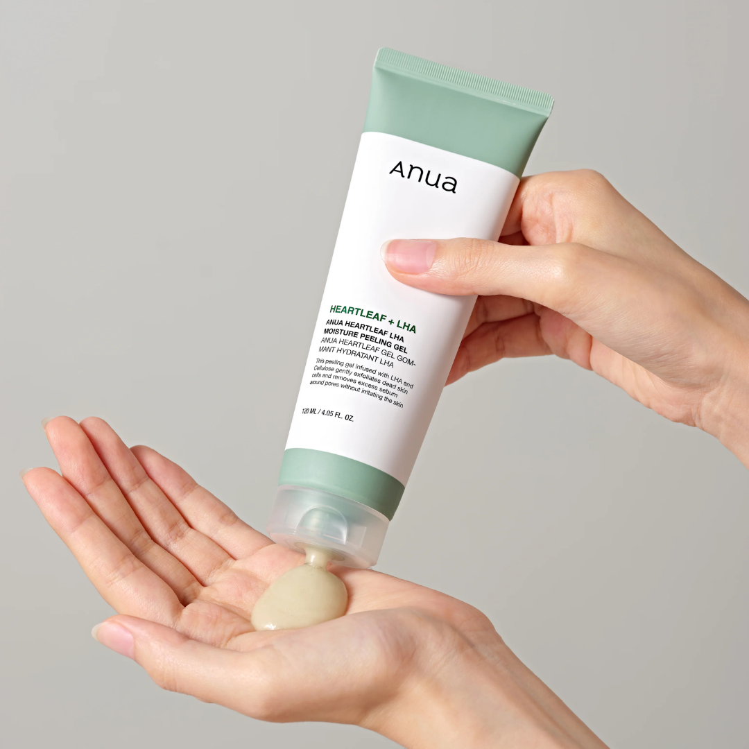 Hand holding a tube of Ahua skincare product with a gray background