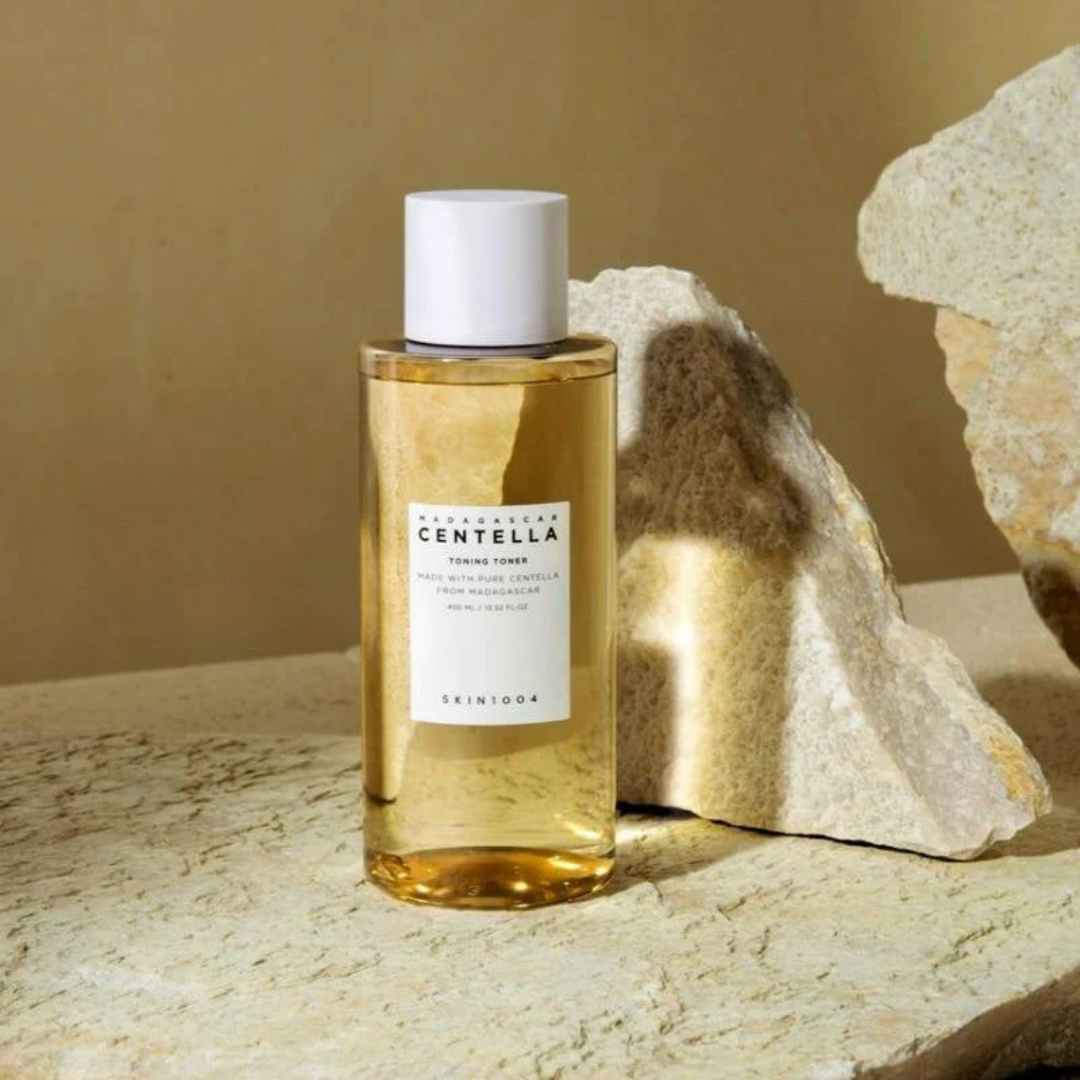 Bottle of Centella water on a textured surface with rocks in the background