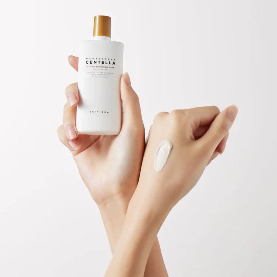 Hand holding a bottle of Centella Asiatica skincare product with a small amount on the palm against a light background.