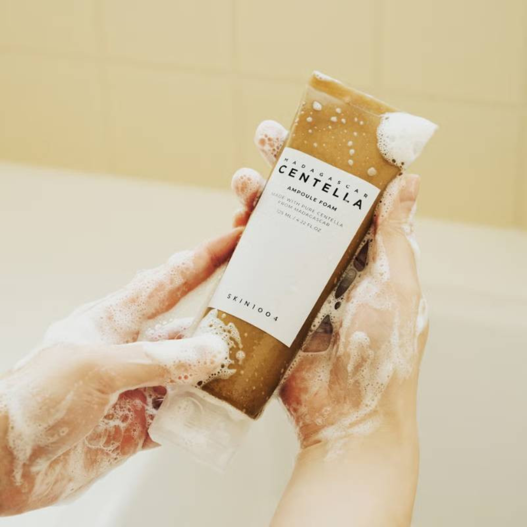 Person holding a Skinfook Centella Asiatica foam cleanser with a beige background