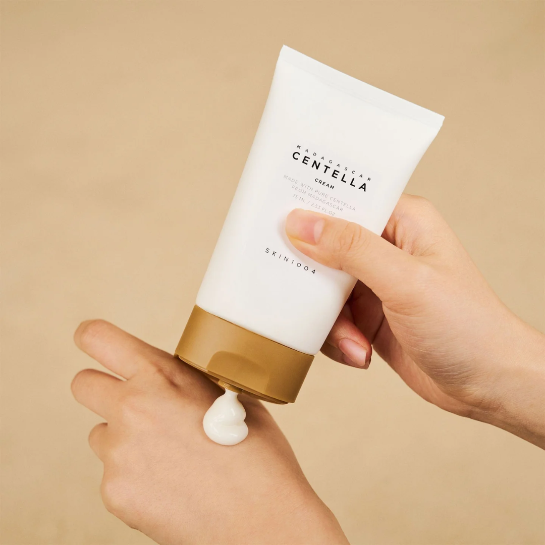 Hand holding a tube of Centella Cream with a beige background