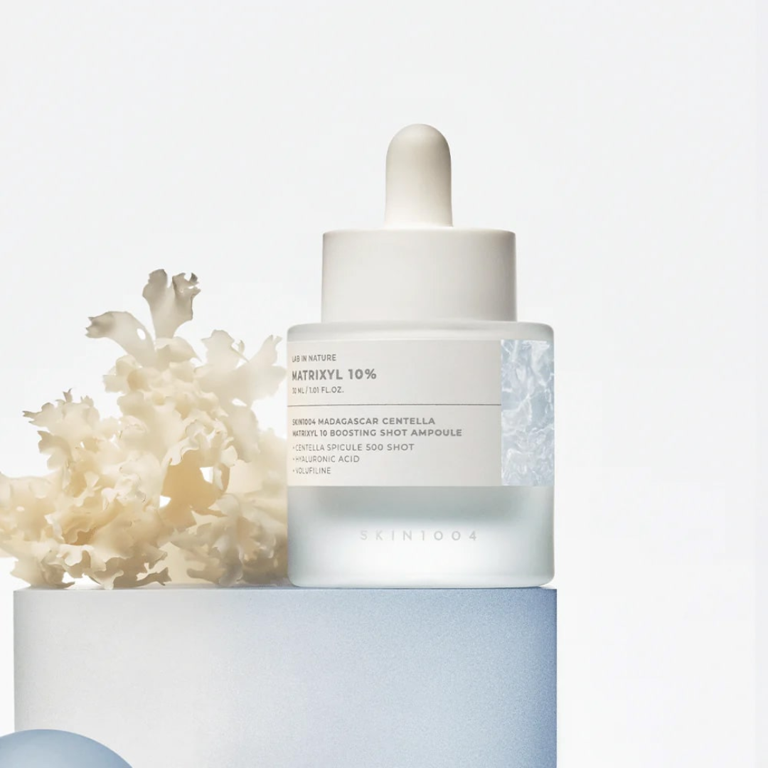 Skincare dropper bottle with coral on a light blue background