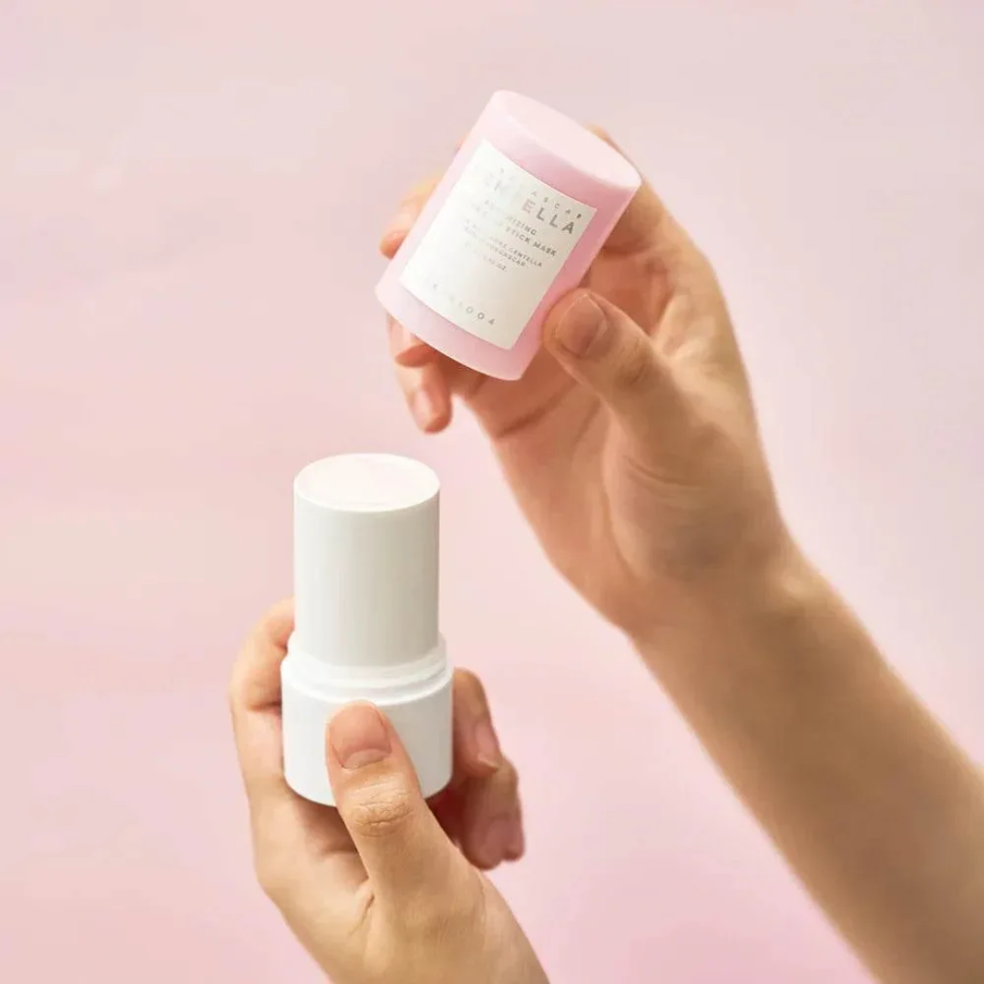 Two skincare products held by hands against a pink background