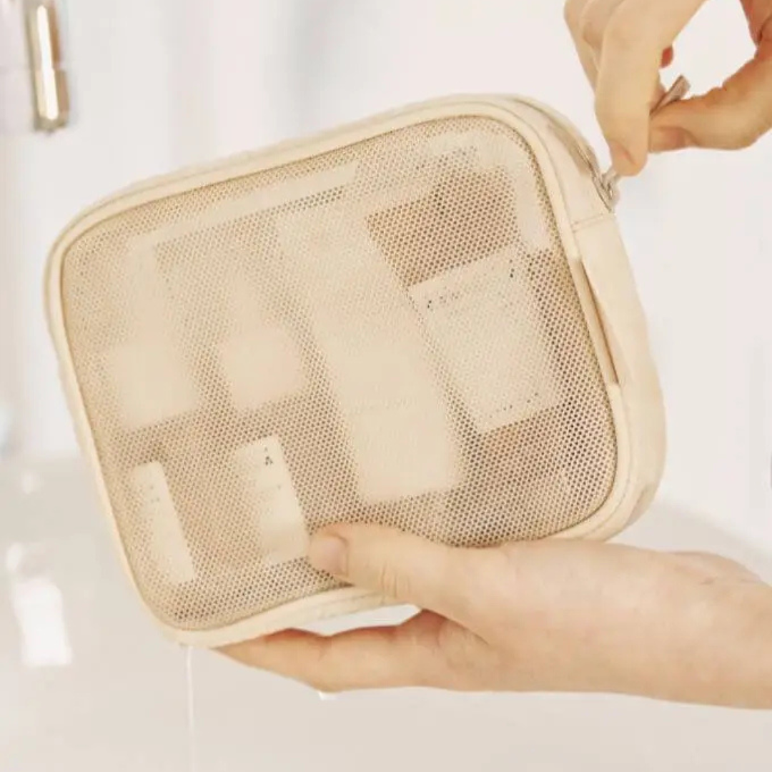 Beige mesh pouch with small containers held by a hand against a light background