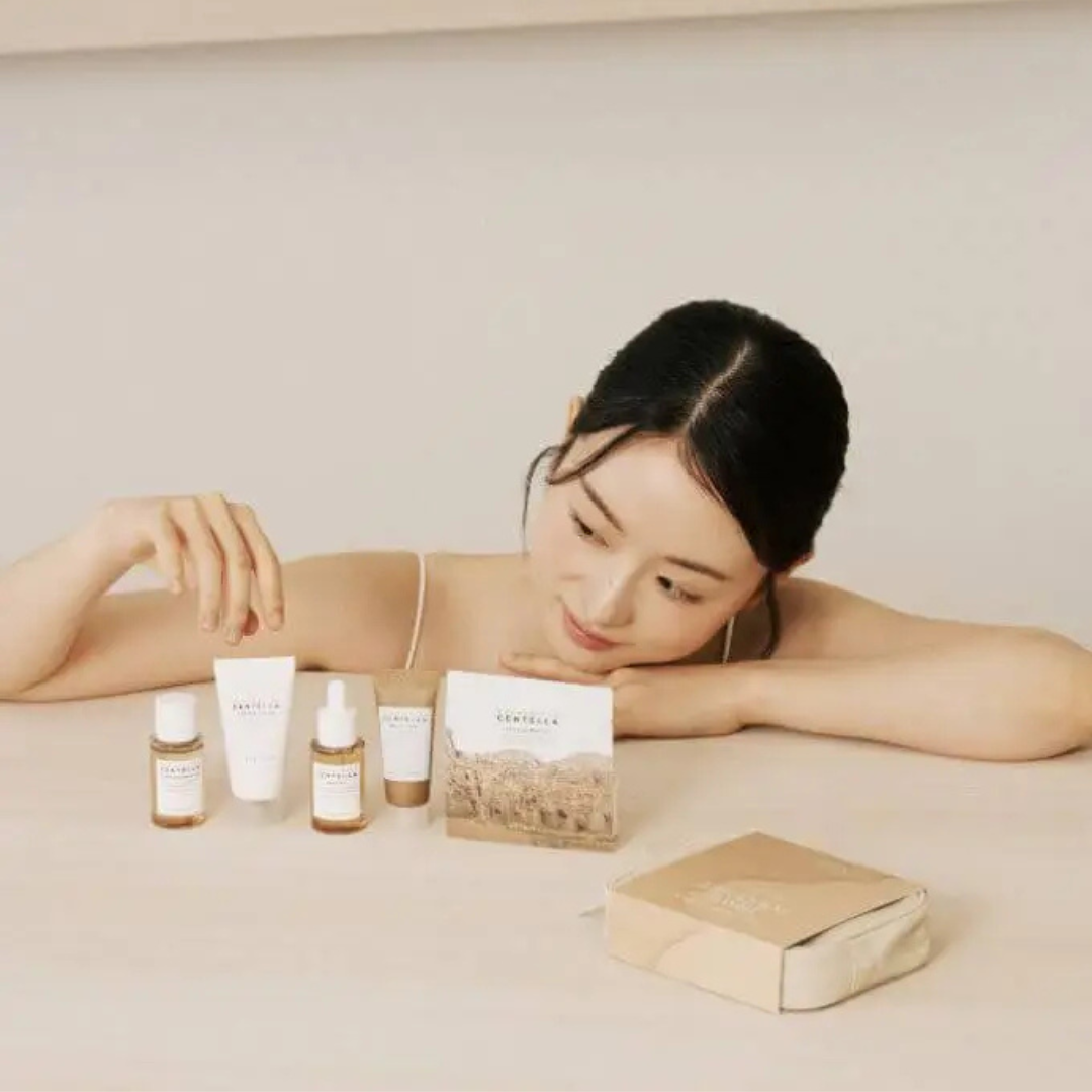 Woman sitting with skincare products on a neutral background