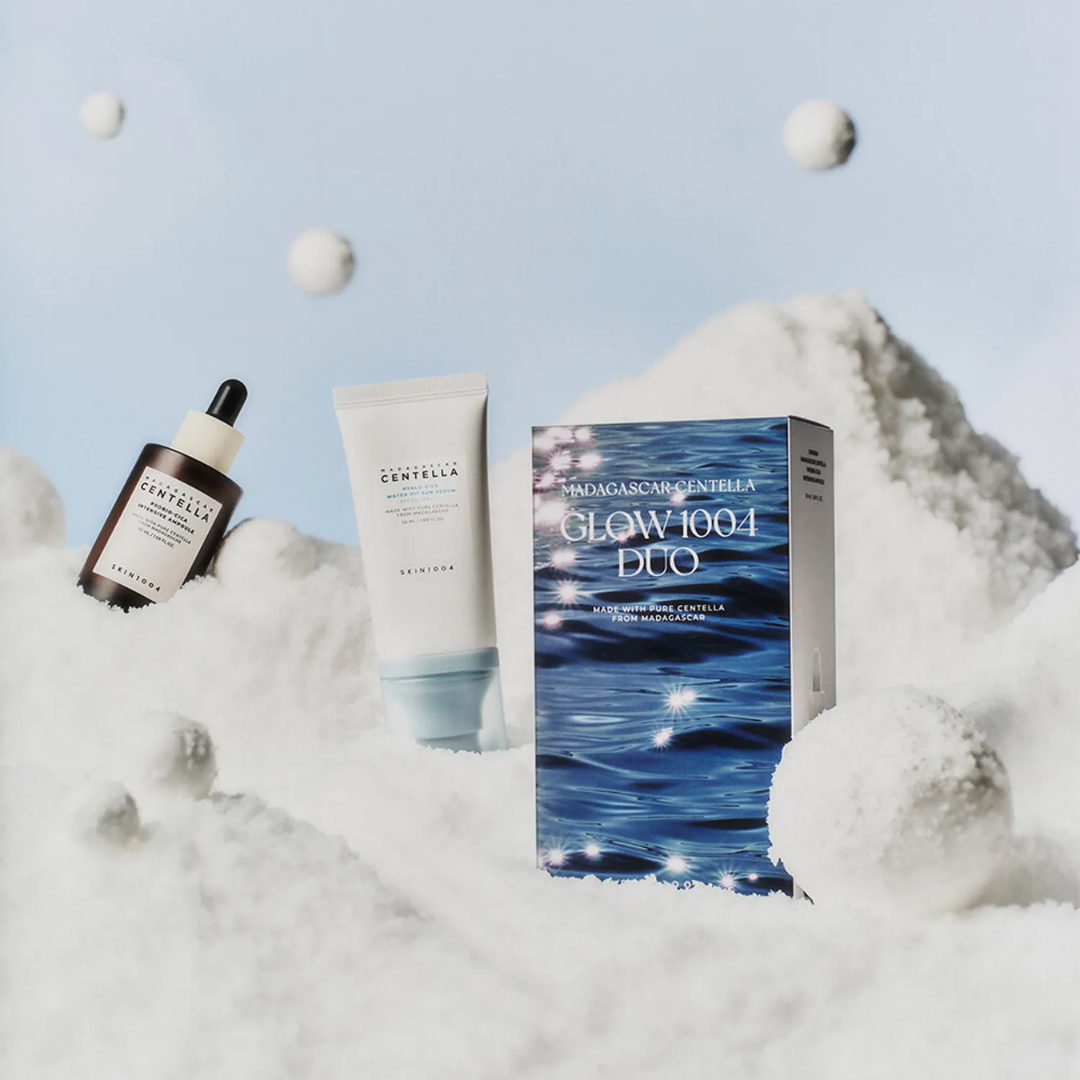 Skincare products including a bottle, tube, and box on a snowy background