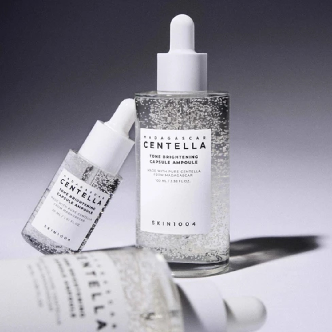 Two skincare bottles with droppers labeled 'Skin1004' on a gray background