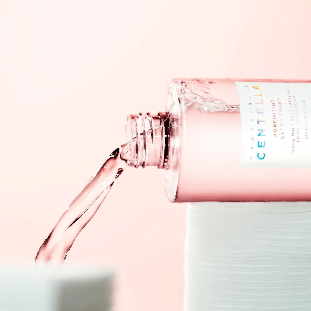 Pink bottle of Centella water being poured on a white background