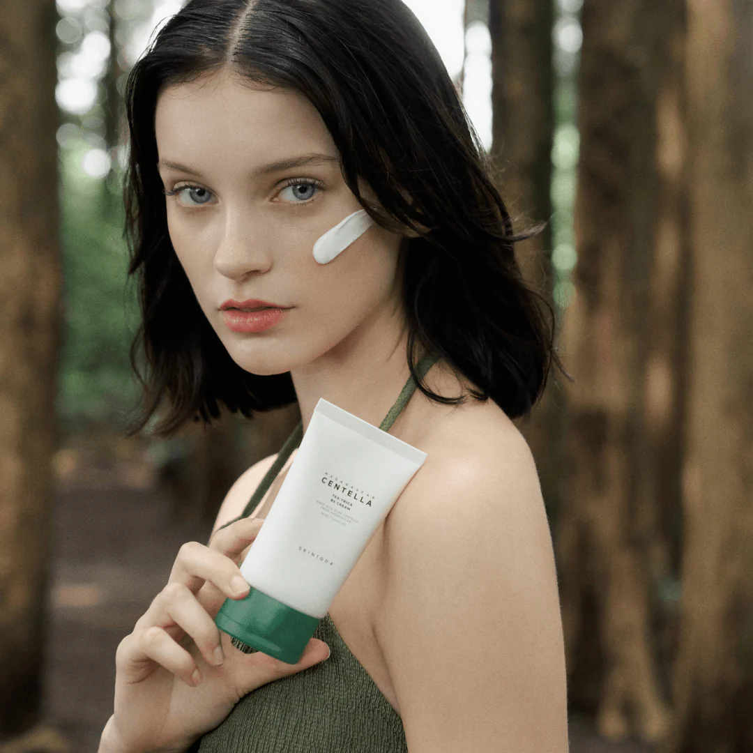 Woman holding a skincare product in a forest setting