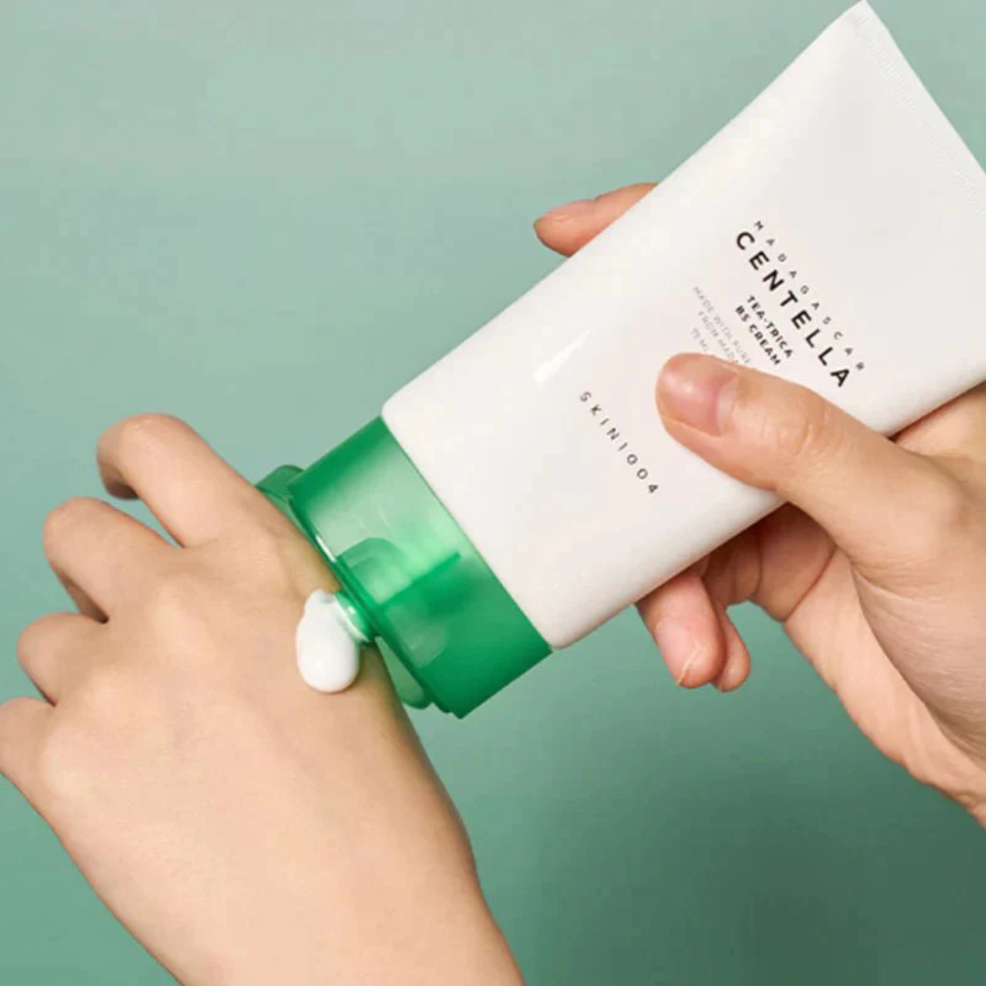 Person applying Centella Asiatica skincare product to wrist with a green background