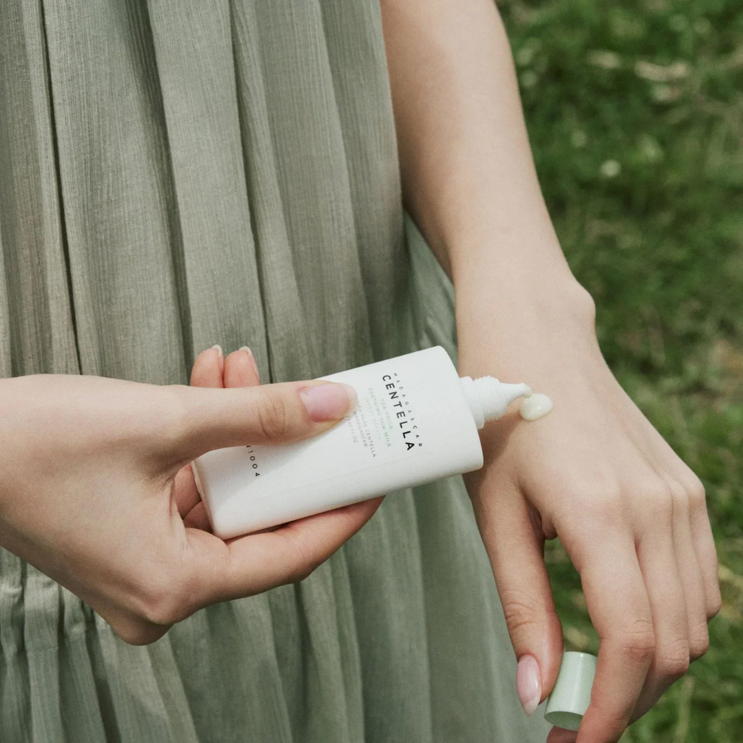 Person applying Centella Asiatica cream to another person's hand outdoors.