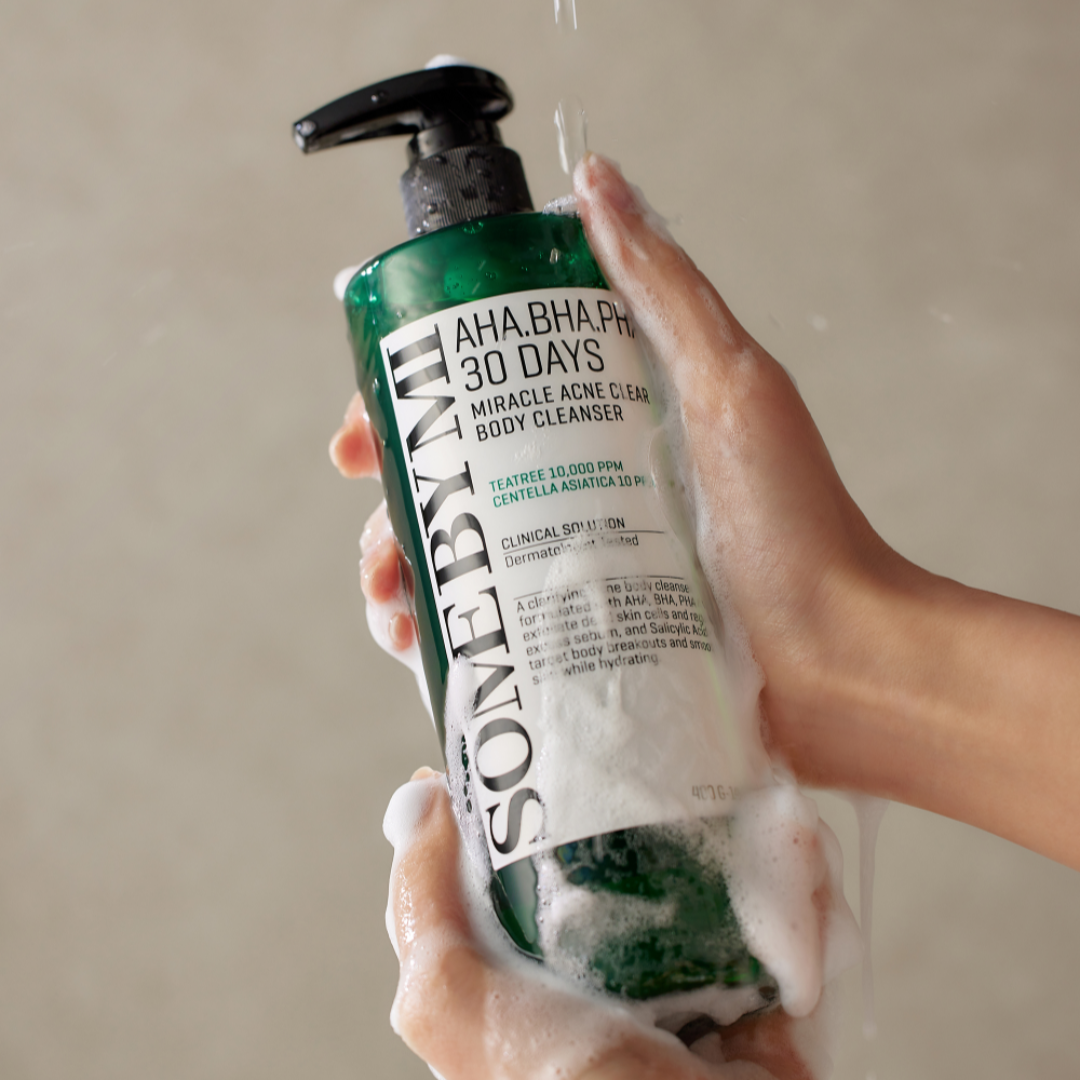 Person holding a bottle of Aha.Bha.Pha 30 Days Miracle Acne Clear Body Cleanser with soap suds.