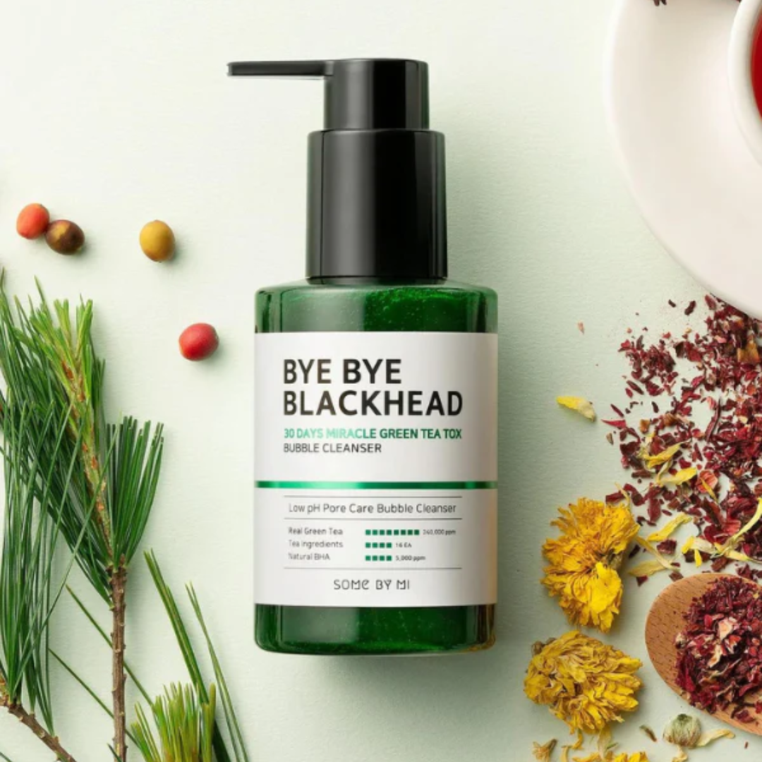 Green bottle of 'Bye Bye Blackhead' cleanser with natural elements on a light background