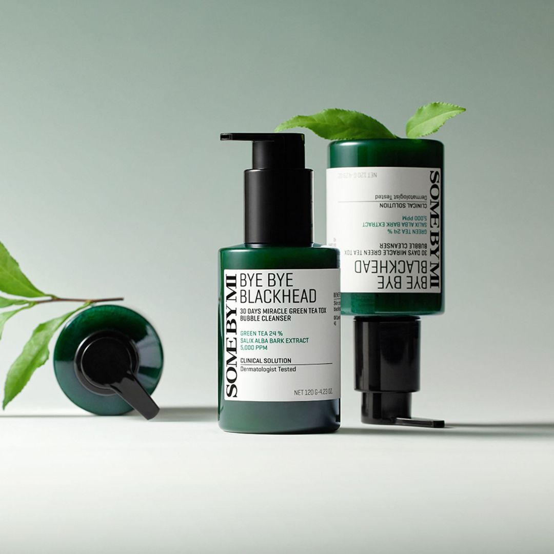 Two skincare bottles with green leaves on a light gray background