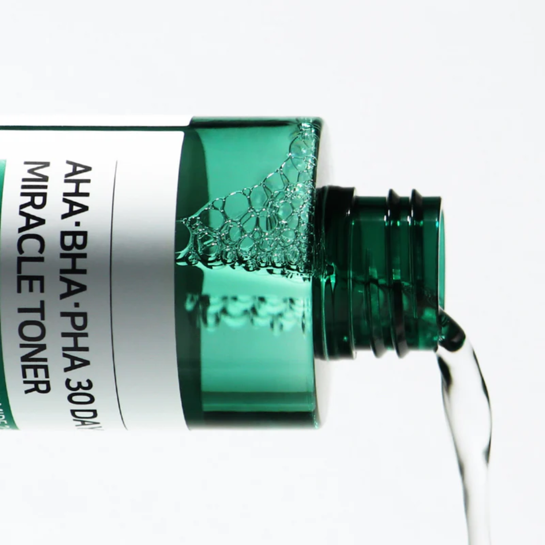 Green skincare toner bottle being squeezed with a white background