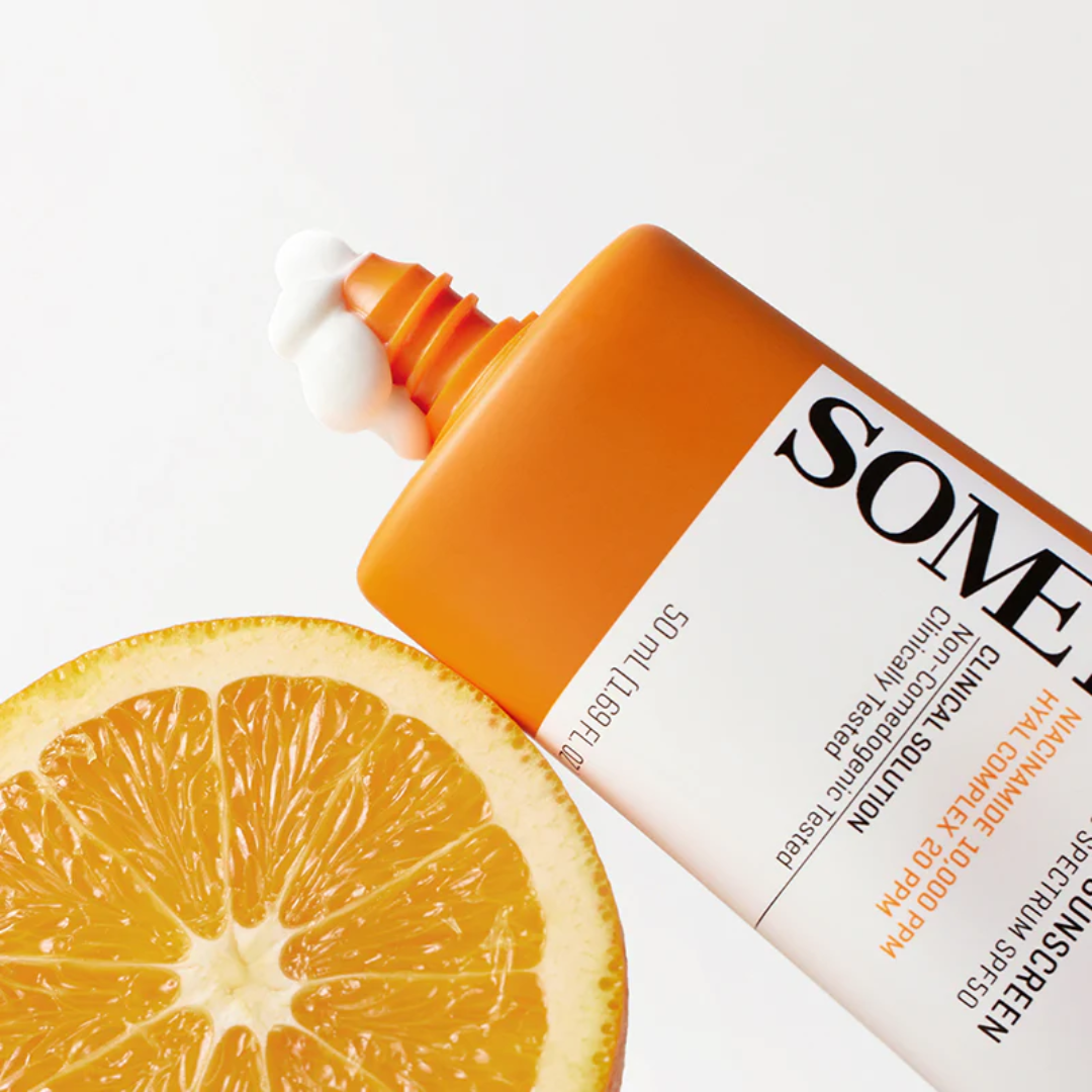 Orange skincare product with a sliced orange on a white background