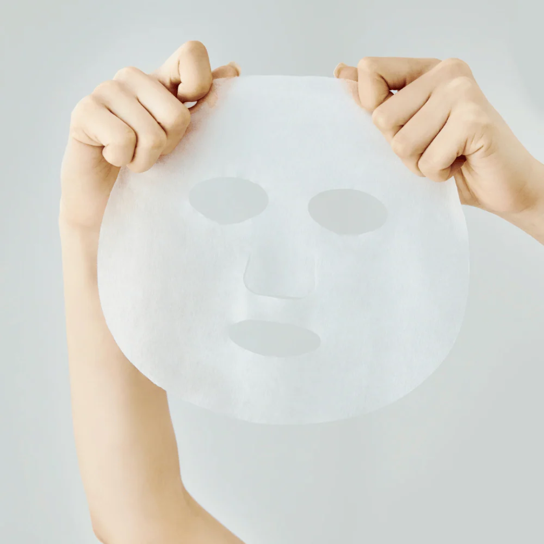 Person holding a white face mask against a light gray background