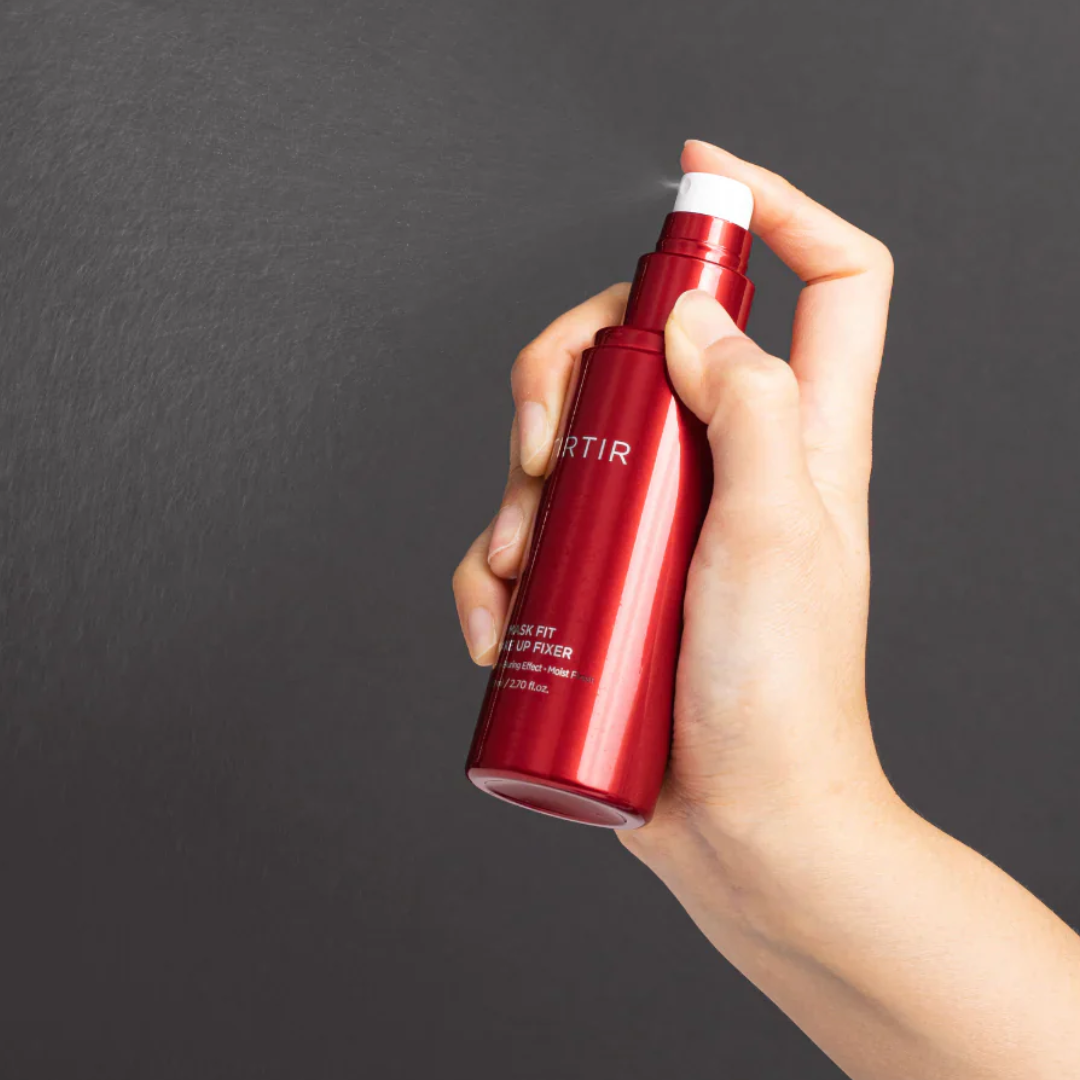 Hand holding a red bottle with a dark background