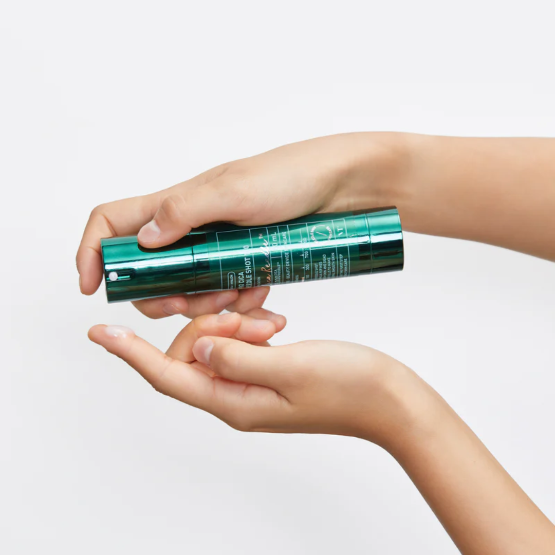 Hand holding a green skincare product against a light background