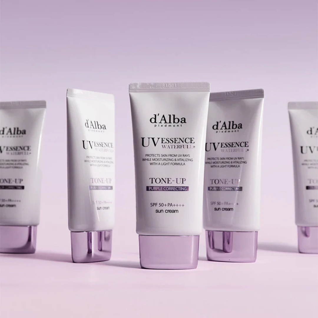 Row of d'Alba UV Essence skincare products on a light purple background