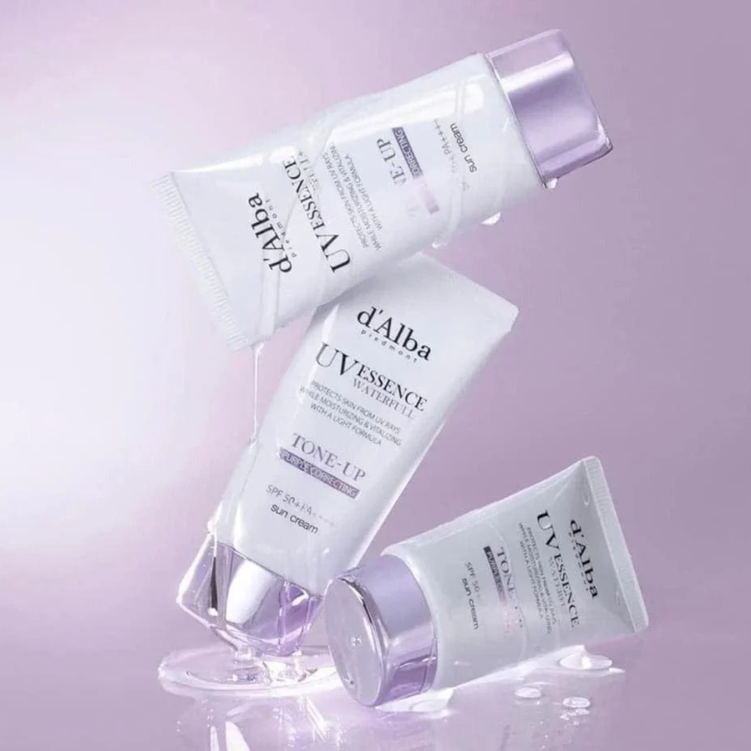 Three bottles of d'Alba UV Essence on a light purple background