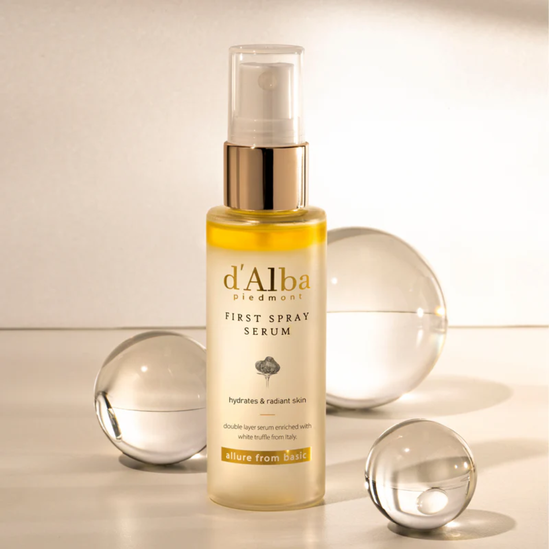 d'Alba First Spray Serum bottle with decorative glass spheres on a neutral background